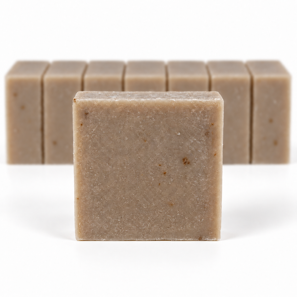 Oatmeal Goat's Milk Soap, with a sharp foreground soap bar and a softly blurred row of bars on a white background.