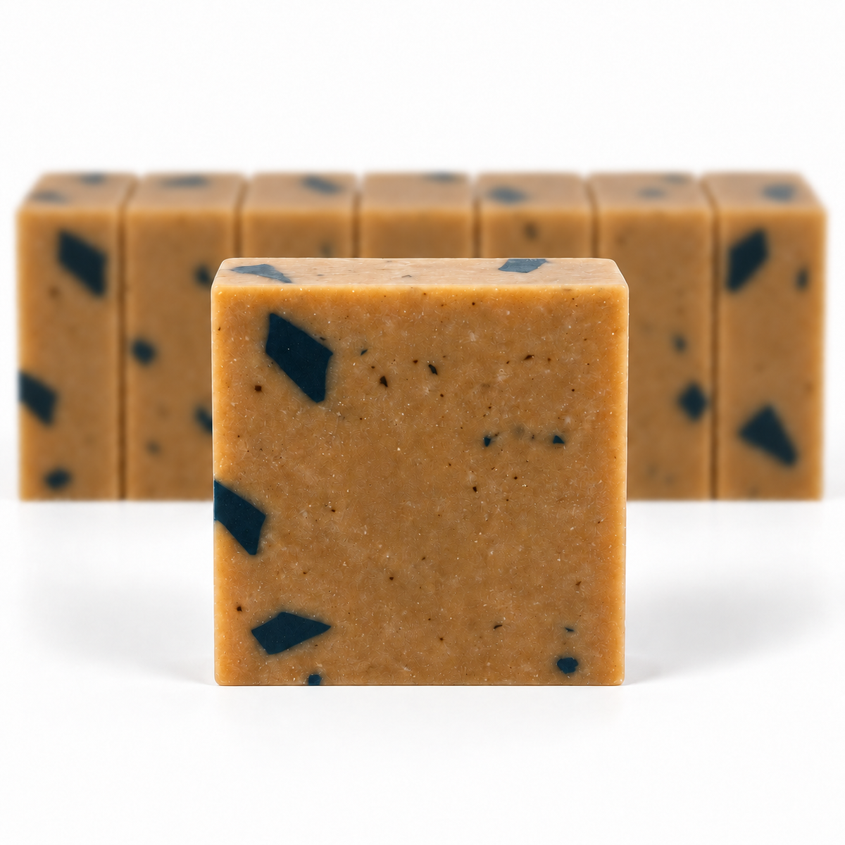Dead Sea Mud, with a sharp foreground soap bar and a softly blurred row of bars on a white background.