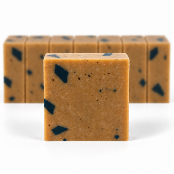 Dead Sea Mud, with a sharp foreground soap bar and a softly blurred row of bars on a white background.