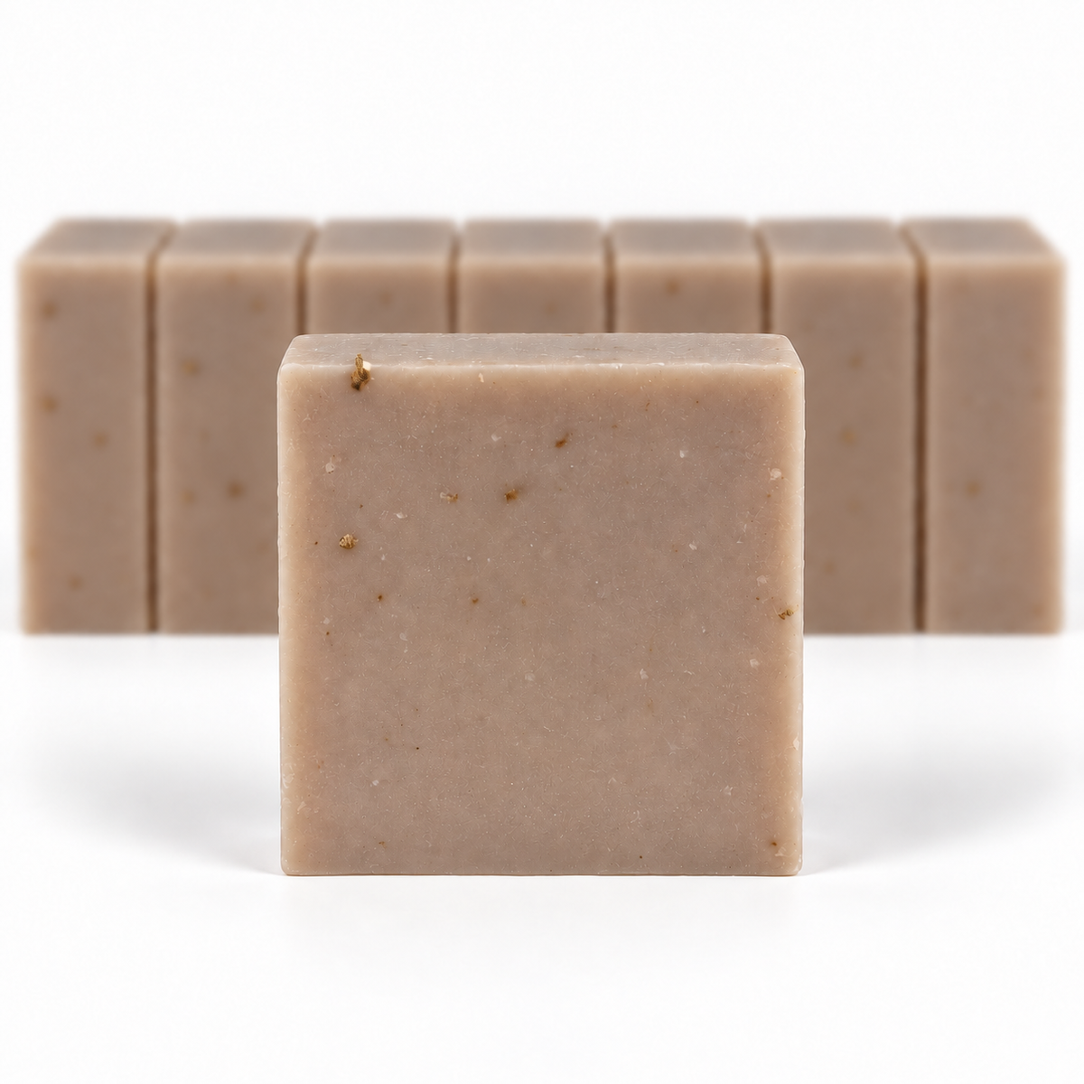 Oatmeal Milk & Organic Honey, with a sharp foreground soap bar and a softly blurred row of bars on a white background.